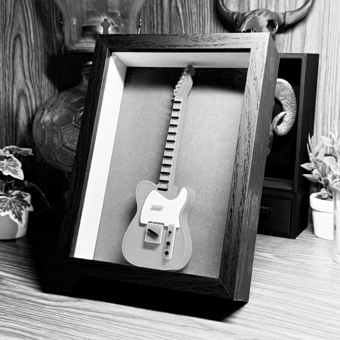 A black and white image of a 3D printed guitar in a shadowbox.