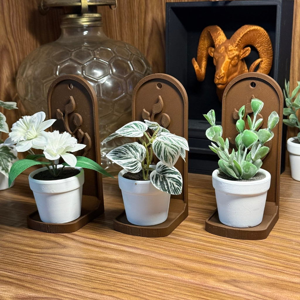 Decorative potted plants on wooden stands with a lamp and ram head sculpture in the background.